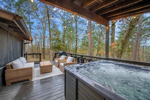An outdoor deck with wicker furniture, a hot tub, and a grill. - Sleeps 18 - Hot Tub - Playground - Games - Firepit (Broken Bow)