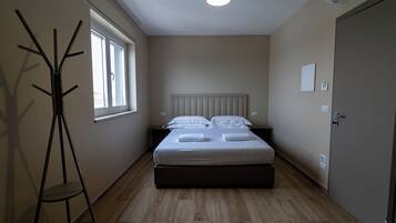 Una camera da letto con un letto, un comodino, una lampada e una finestra.