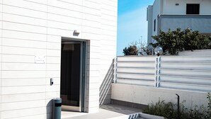 A modern building entrance with a door, a trash bin, and a staircase leading to a higher level. - D'Stay (Bari)