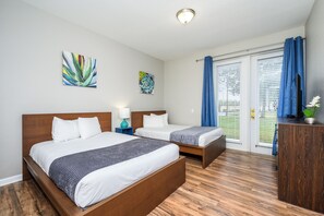 Ein Hotelzimmer mit zwei Betten, Holzboden, Schreibtisch und einem Fenster mit Vorhängen.
