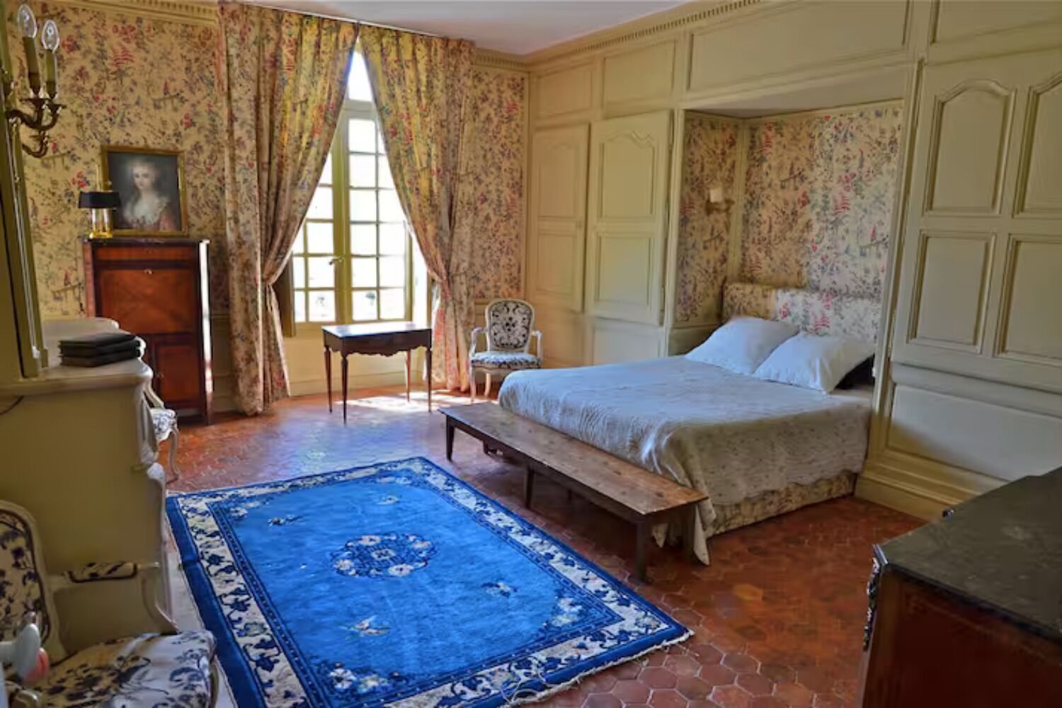 Une chambre à coucher avec un lit, une chaise, un bureau et une fenêtre.