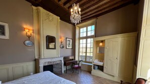 A bedroom with a large bed, a fireplace, a desk, and a window with a view. - Gite des Cerfs (La Ferté-Saint-Aubin)