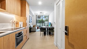 A modern kitchen with wooden cabinets, a built-in oven, and a dining area with a round table and chairs. - 1BR in Miami Worldcenter | Pool + Brightline (Miami)