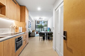 A modern kitchen with wooden cabinets, a built-in oven, and a dining area with a round table and chairs. - 1BR in Miami Worldcenter | Pool + Brightline (Miami)