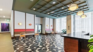 A modern hotel lobby with a geometric patterned floor, seating areas, and a reception desk. - Rooftop Pool Studio in Miami Worldcenter (Miami)