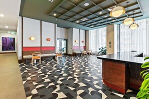 Eine moderne Hotelhalle mit einem geometrisch gemusterten Boden, Sitzbereichen und einer Rezeption.