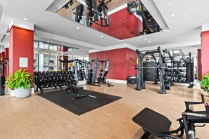 Ein modernes Fitnessstudio mit verschiedenen Trainingsgeräten, einer schwarzen Matte und Topfpflanzen.