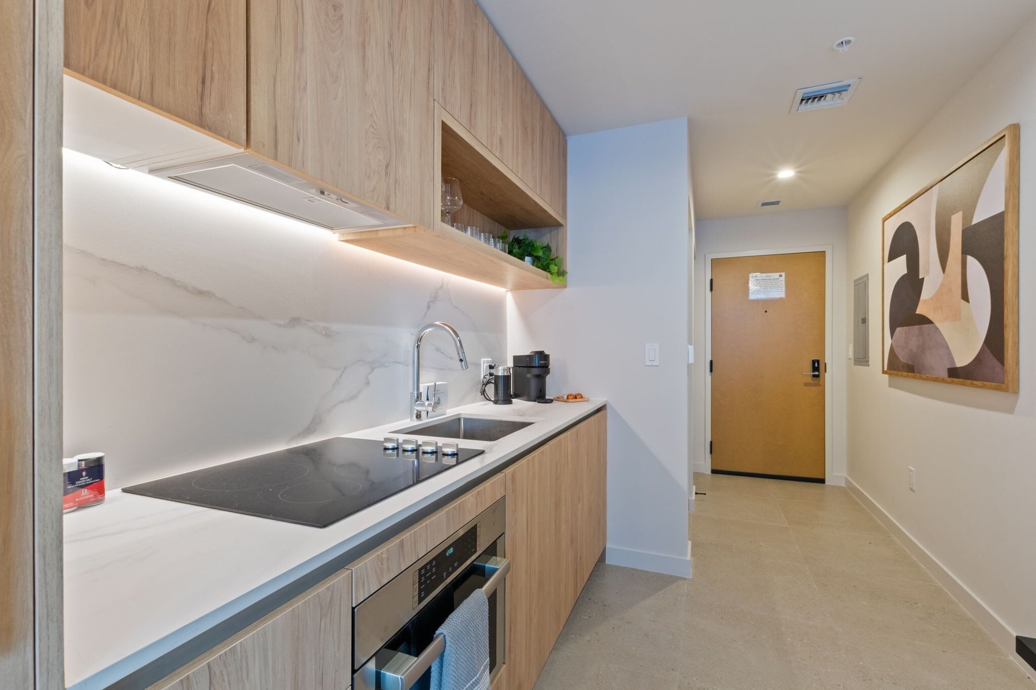 A modern kitchen with a double sink, wooden cabinets, and a built-in oven.