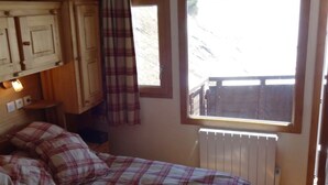 Ein Schlafzimmer mit Bett, Fenster und Heizkörper.