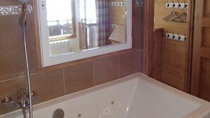 Ein Badezimmer mit einer großen Badewanne, einer Dusche und einem Spiegel.