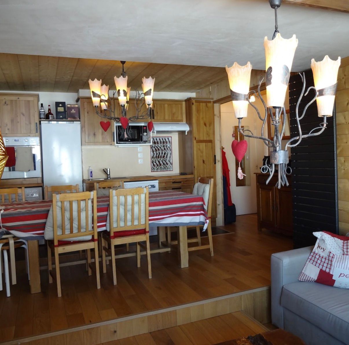 A cozy cabin-style room with a dining area, wooden furniture, and a unique chandelier.