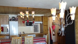 Ein gemütliches Blockhauszimmer mit Essbereich, Holzmöbeln und einem besonderen Kronleuchter.