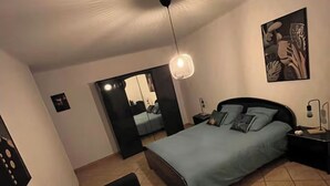 Una camera da letto con un letto, un divano, un comodino, una lampada a muro e uno specchio.