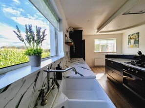 A modern kitchen with a large window, a marble countertop, and a built-in sink. - The Discovery Lodge - Sleep in Luxury, Wake to Mountains (County Derry)