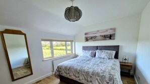 Ein Schlafzimmer mit einem großen Bett, einem Fenster, einem Spiegel und einem Wandbild.