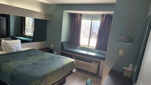Une chambre d’hôtel avec un lit, un bureau et une fenêtre avec des rideaux.
