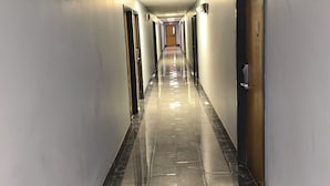 Un long couloir étroit, doté d’un sol carrelé brillant, de portes des deux côtés et d’un plafond pourvu d’un éclairage encastré.