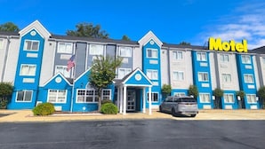 Un motel à la façade bleue et blanche, avec une enseigne bien visible indiquant « Motel » et un drapeau américain.