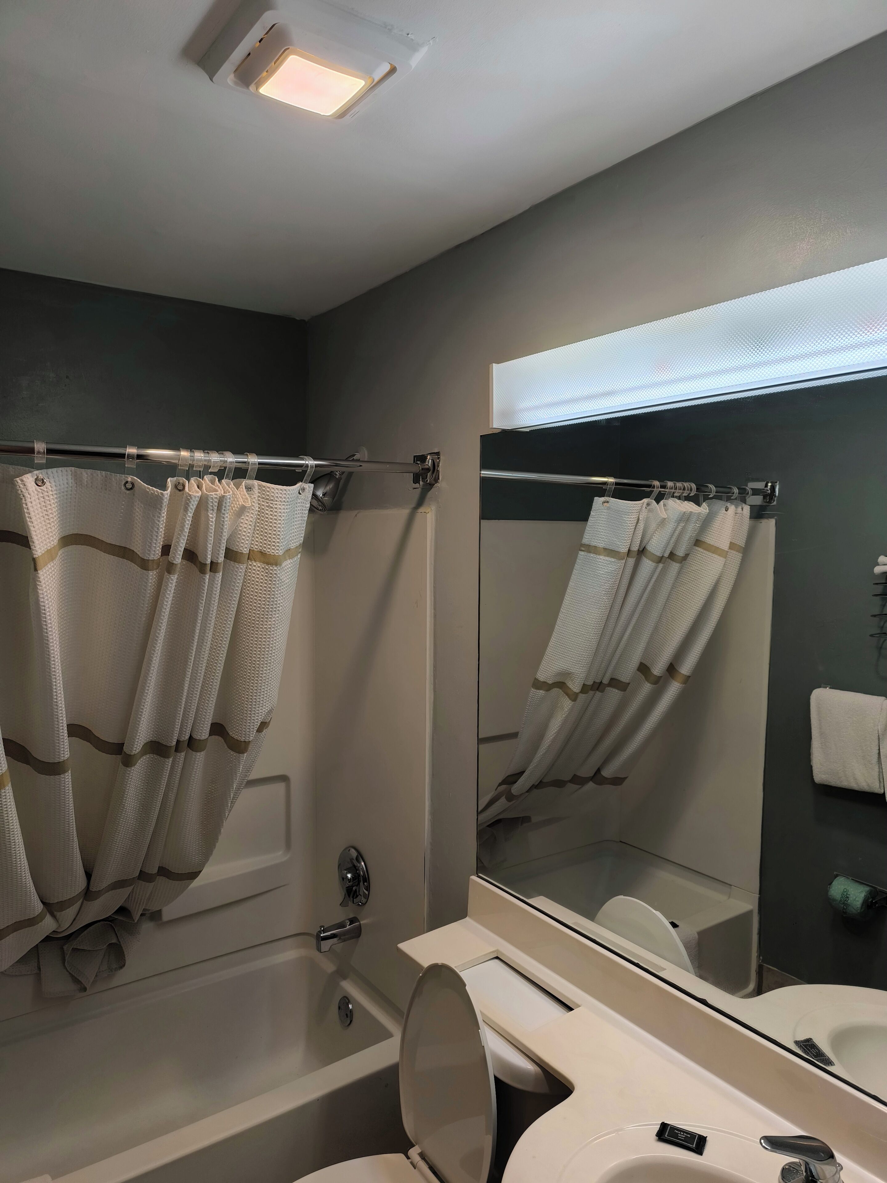 Een badkamer met een bad, toilet, wastafel en een grote spiegel.