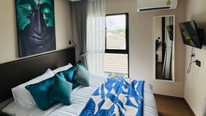 Habitación de hotel con cama, un cuadro, equipo de aire acondicionado y ventana con vistas.