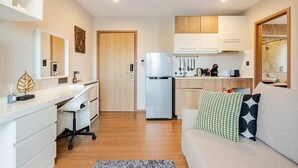 Cocina compacta con refrigerador, comedor y sofá con cojín estampado.