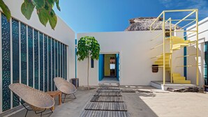 A modern outdoor area with a wooden deck, wicker chairs, a staircase, and a thatched-roof structure. - Casa Quetzal - Private beachfront villa - Swimming pool & total peace & quiet (Puerto Escondido)