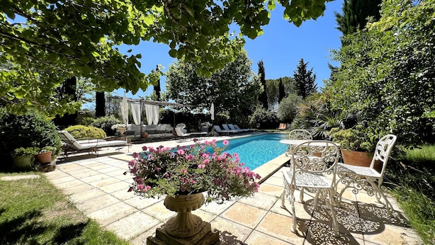 Un espace piscine aménagé avec des chaises longues, une table et un pot de fleurs.