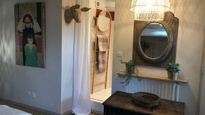 Une salle de bain avec un rideau de douche, une échelle en bois, un miroir et une étagère en bois ornée de plantes.