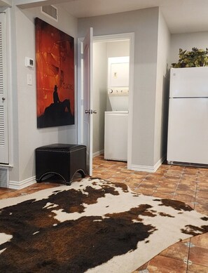 Eine Küche mit einem weißen Kühlschrank, einer Waschmaschine und einem Kuhfellteppich.