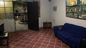 Ein Wohnzimmer mit einem gemusterten Boden, einem blauen Sofa, einem Fernseher und einem Bild an der Wand.