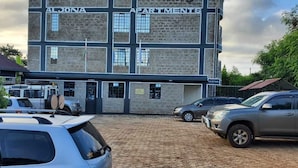 Een gebouw met de naam 'ALJONDA APARTMENTS', met een bakstenen gevel, meerdere ramen en een hekwerk.