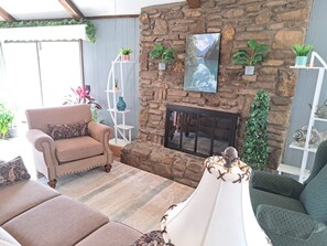 A cozy living room with a stone fireplace, a sofa, a chair, and a lamp. - Bears Den-Secluded cove, Lakefront Cabin, Lake access and amazing lake view (Garfield)