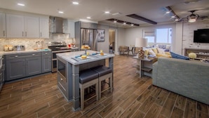 Una cocina moderna con armarios grises, una isla central y una zona de comedor con una mesa y sillas.