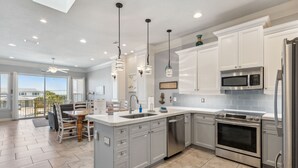 Una cocina moderna con armarios grises, electrodomésticos de acero inoxidable e iluminación colgante.