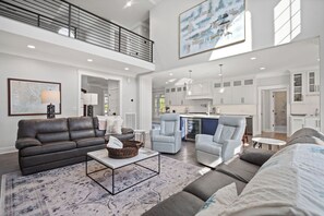 A spacious living area with a high ceiling, a dining area, and a kitchen. - "Fripp Well Done" - 147 Ocean Creek (Fripp Island)