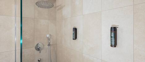 Un baño moderno con cabina de ducha de vidrio, un cabezal de ducha manual y dos grifos empotrados.
