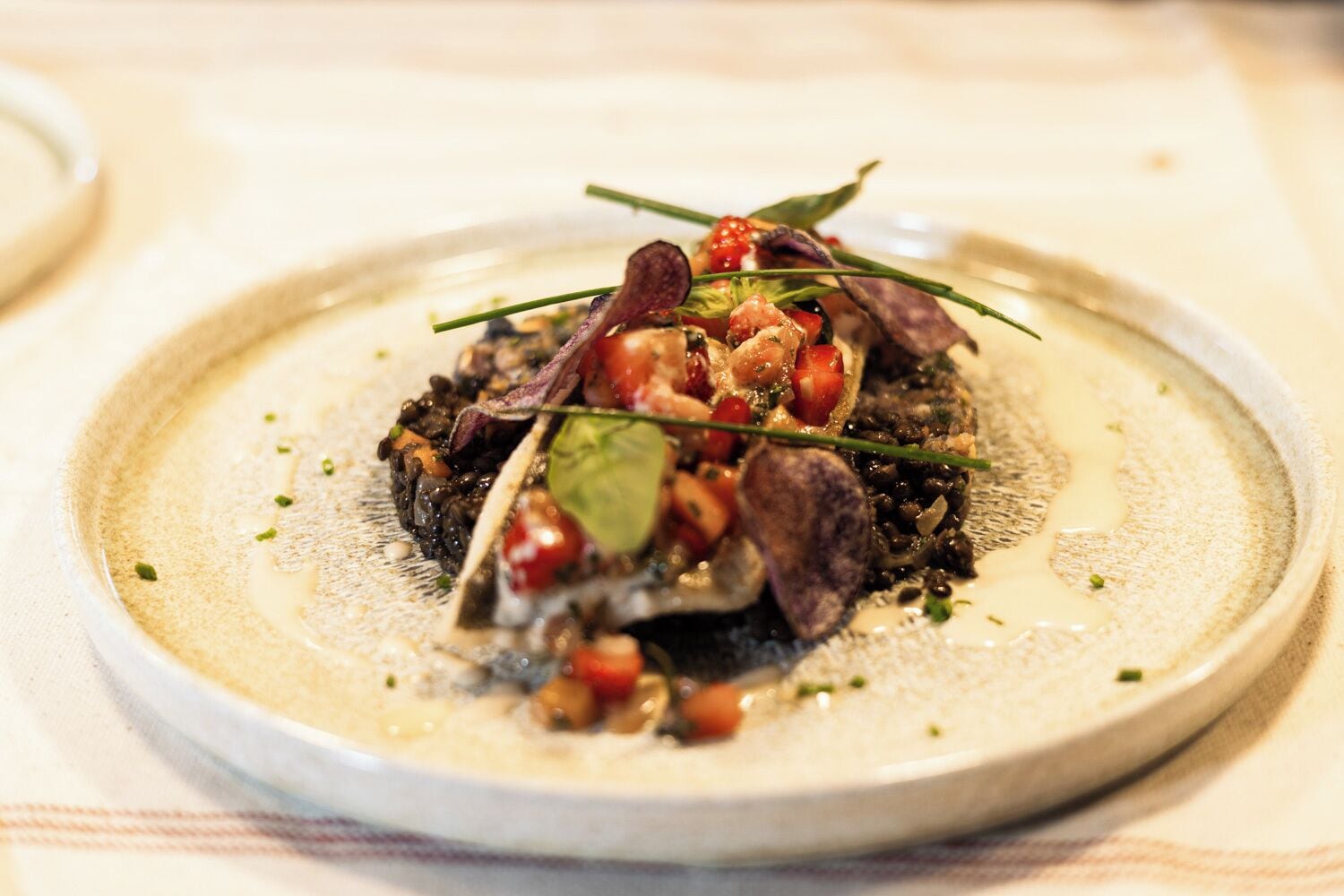 Un plato de comida con una variedad de ingredientes, como verduras de hoja, tomates y quizás carne, sobre un plato de cerámica.