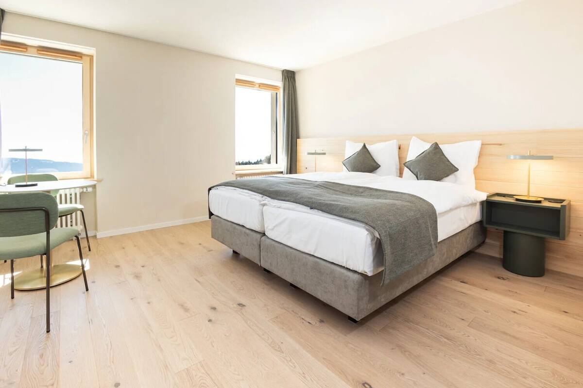 Une chambre d’hôtel moderne avec un grand lit, un bureau et une vue par la fenêtre.