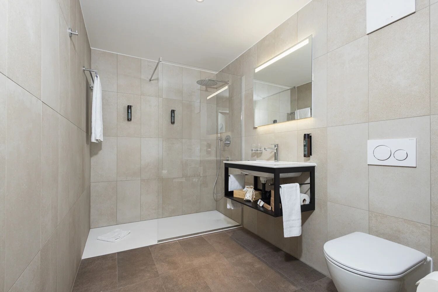 A modern bathroom with a walk-in shower, a vanity with a mirror, and a toilet.