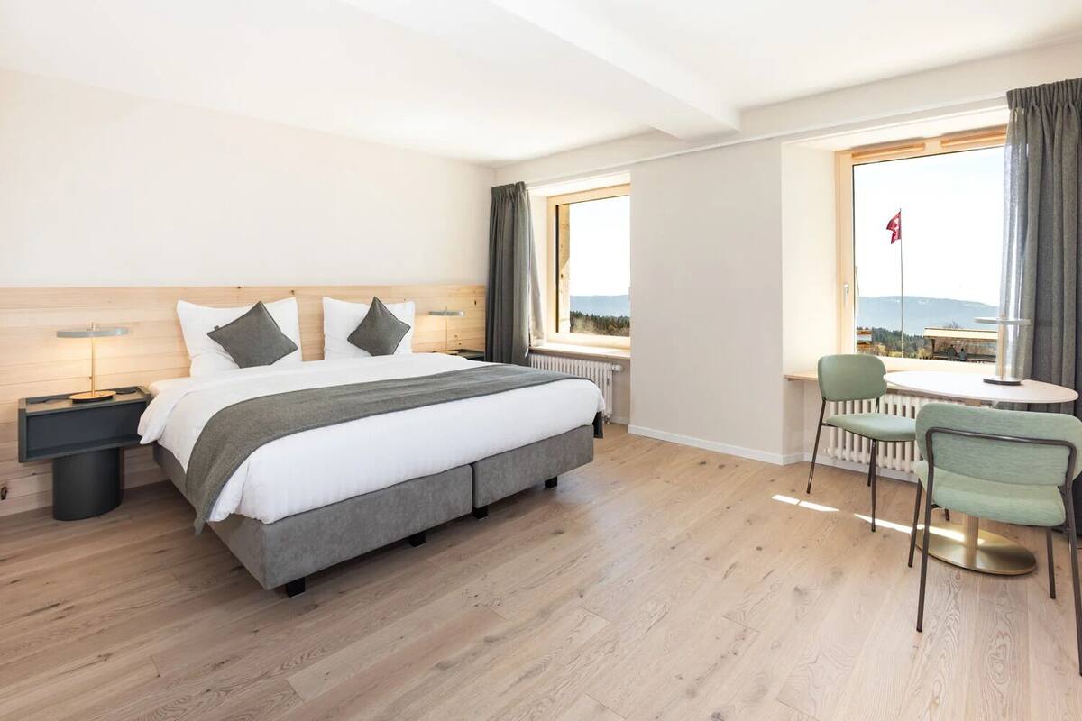 Une chambre d’hôtel avec un lit, une table de chevet, une lampe et une vue sur l’extérieur.