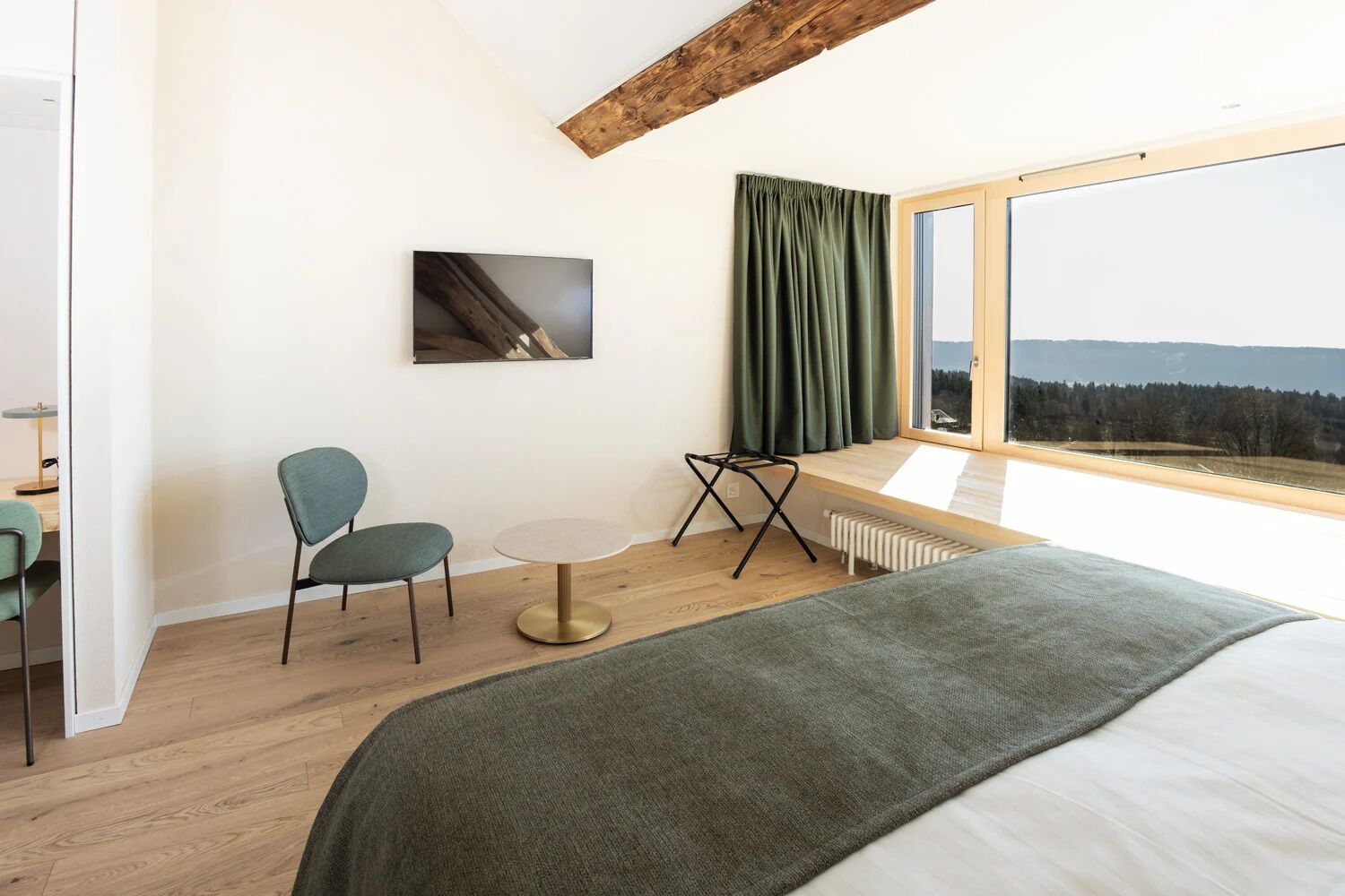 Ein Schlafzimmer mit einem großen Bett, einem Fenster mit Aussicht, einem kleinen Tisch, zwei Stühlen und einem Bild an der Wand.