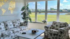 Een woonkamer met een groot raam, een plafondventilator en een wereldkaart aan de muur.