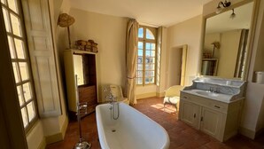 A bathroom with a freestanding bathtub, a vanity with a sink, and a large mirror. - Chambre Lucullus - A night in the heart of the castle (La Ferté-Saint-Aubin)