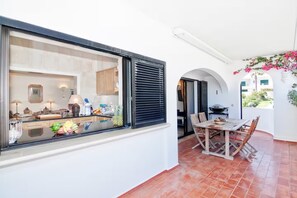 Eine moderne Küche mit großem Fenster, einem Essbereich mit Tisch und Stühlen sowie Blick ins Freie.