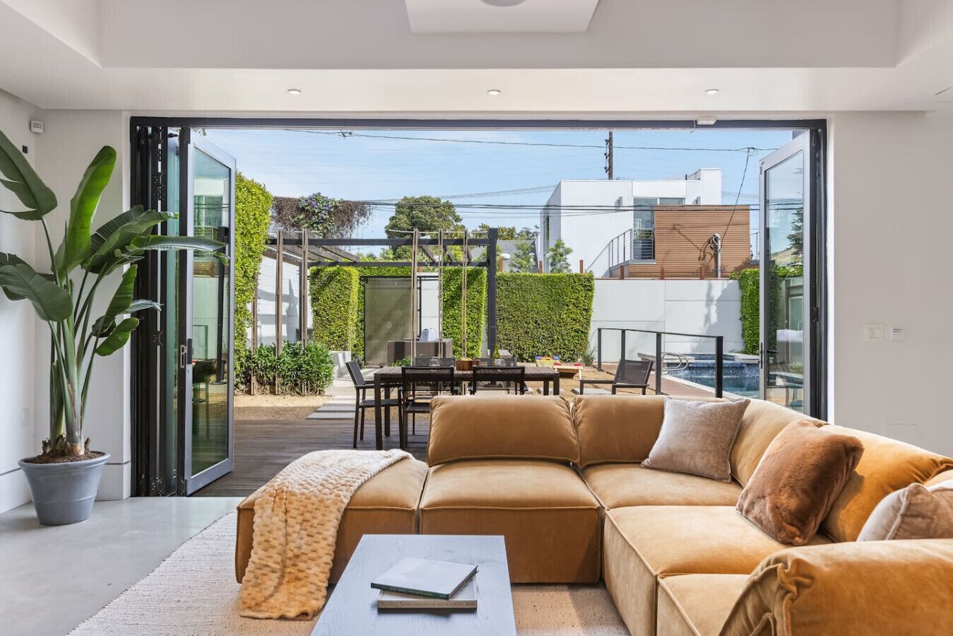 A modern living room with a sofa, coffee table, and a view of an outdoor patio area with a table and chairs.