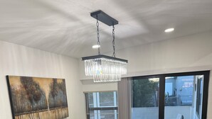 Ein Essbereich mit einem großen Holztisch, vier Stühlen, einer Pendelleuchte und einem Gemälde an der Wand.