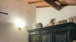 A bedroom with a bed, a wooden cabinet, a wall-mounted light, and a ceiling with exposed beams. - Il Poggetto di Barbara - Casa Bianca (Scansano)