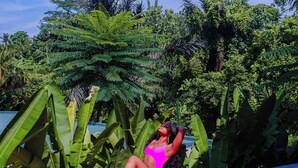 A person sitting on a flower-decorated pathway surrounded by lush greenery. - Lovely 2-bedroom villa with AC in beautiful Ubud Bali (Bali)