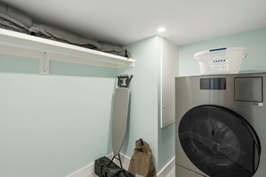 A laundry room with a washing machine, a drying rack, a bag, and a basket. - Wake Up to the Gulf – Beachfront Living (Siesta Key)