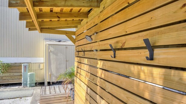 Pared exterior de madera con tablones horizontales y ganchos metálicos.